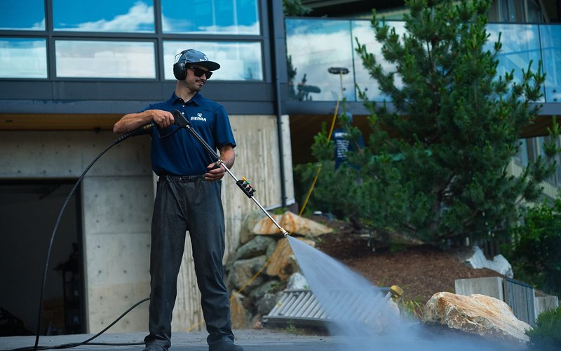 Property services crew member pressure washing a driveway at a Whistler home